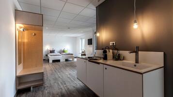 A modern kitchen with a built-in sink, a coffee machine, and a dining area with a white table and chairs.