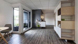 A modern kitchen with a wooden floor, a built-in white cabinet, and a glass door leading to a balcony.