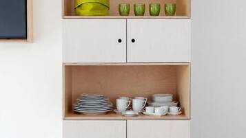 Un mueble de madera minimalista con tres estantes, cada uno con utensilios de cocina.