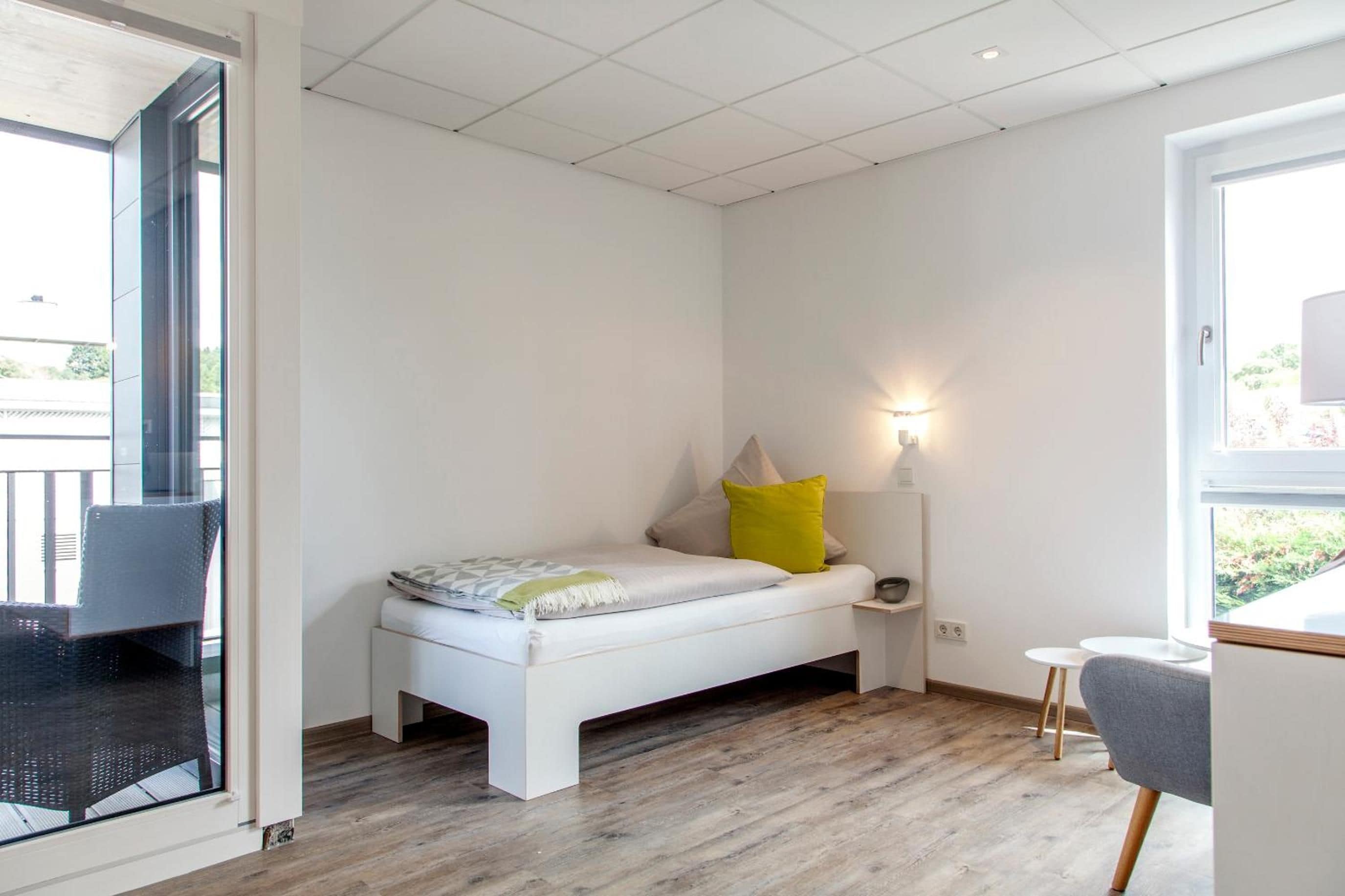 Een moderne slaapkamer met een bed, nachtkastje, lamp en uitzicht op het omliggende landschap.