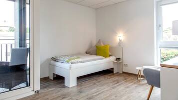 Een moderne slaapkamer met een bed, nachtkastje, lamp en uitzicht op het omliggende landschap.