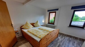 Un dormitorio con cama de madera, ventana con vistas y radiador.