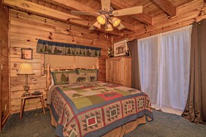 A wooden cabin bedroom with a bed, a nightstand, a lamp, a ceiling fan, and a window with curtains. - ClearView: MtnView! Hot Tub, Wifi, Game Room, Resort Pool, near Dollywood (Sevierville)