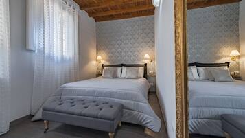 Une chambre avec deux lits, un grand miroir et deux lampes fixées au mur.