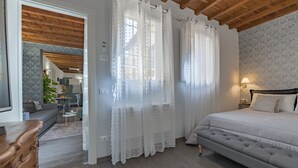Une chambre avec un grand lit, un plafond en bois et une vue sur le salon.