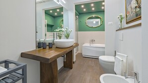 Une salle de bain moderne avec un meuble-lavabo en bois, un grand miroir, une baignoire sur pieds et un lavabo blanc.