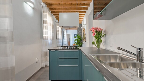 Une cuisine moderne avec des meubles de couleur turquoise, des éviers en acier inoxydable et un plafond en bois.