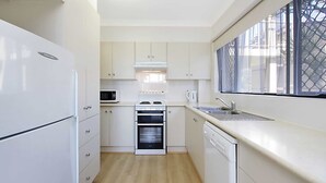 Eine moderne Küche mit weißen Schränken, einem eingebauten Backofen, einer Mikrowelle und einem Geschirrspüler.