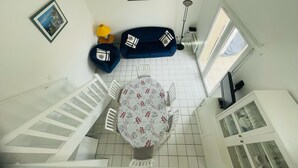 A high-ceilinged room with a dining table, two sofas, and a floor lamp. - Agréable pavillon 6 personnes dans résidence avec piscine (009) (Biscarrosse)