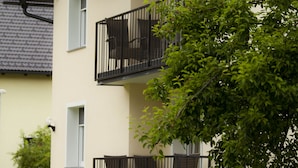 Un immeuble à plusieurs étages doté de balcons, avec une fenêtre bien visible et un arbre au premier plan.