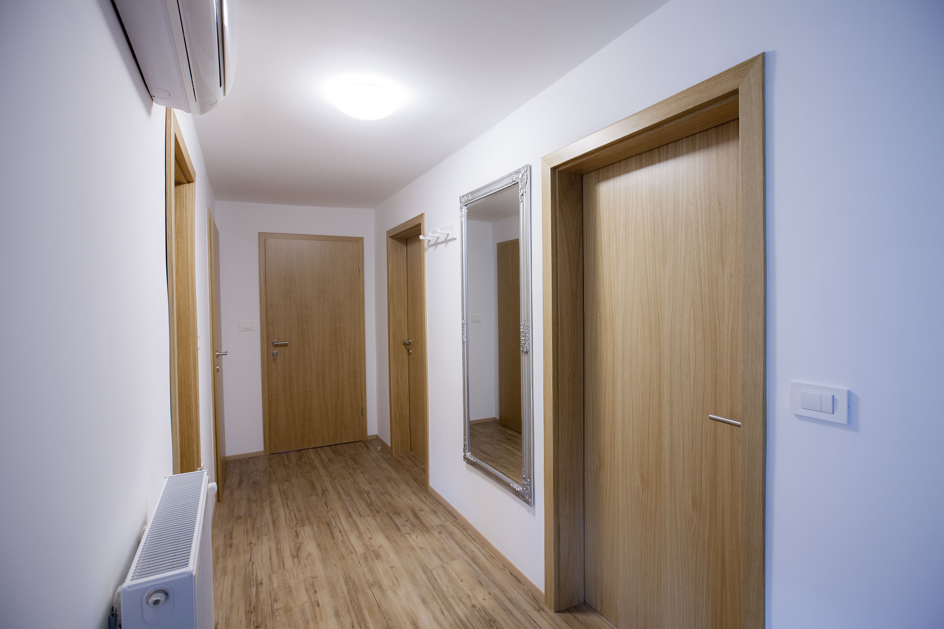 A hallway with wooden doors, a radiator, and a mirror on the wall.