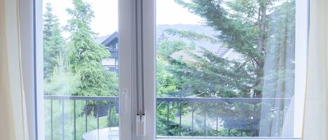Ein Zimmer mit Blick auf einen Balkon, einem Heizkörper und einem mit Vorhängen ausgezogenen Fenster.
