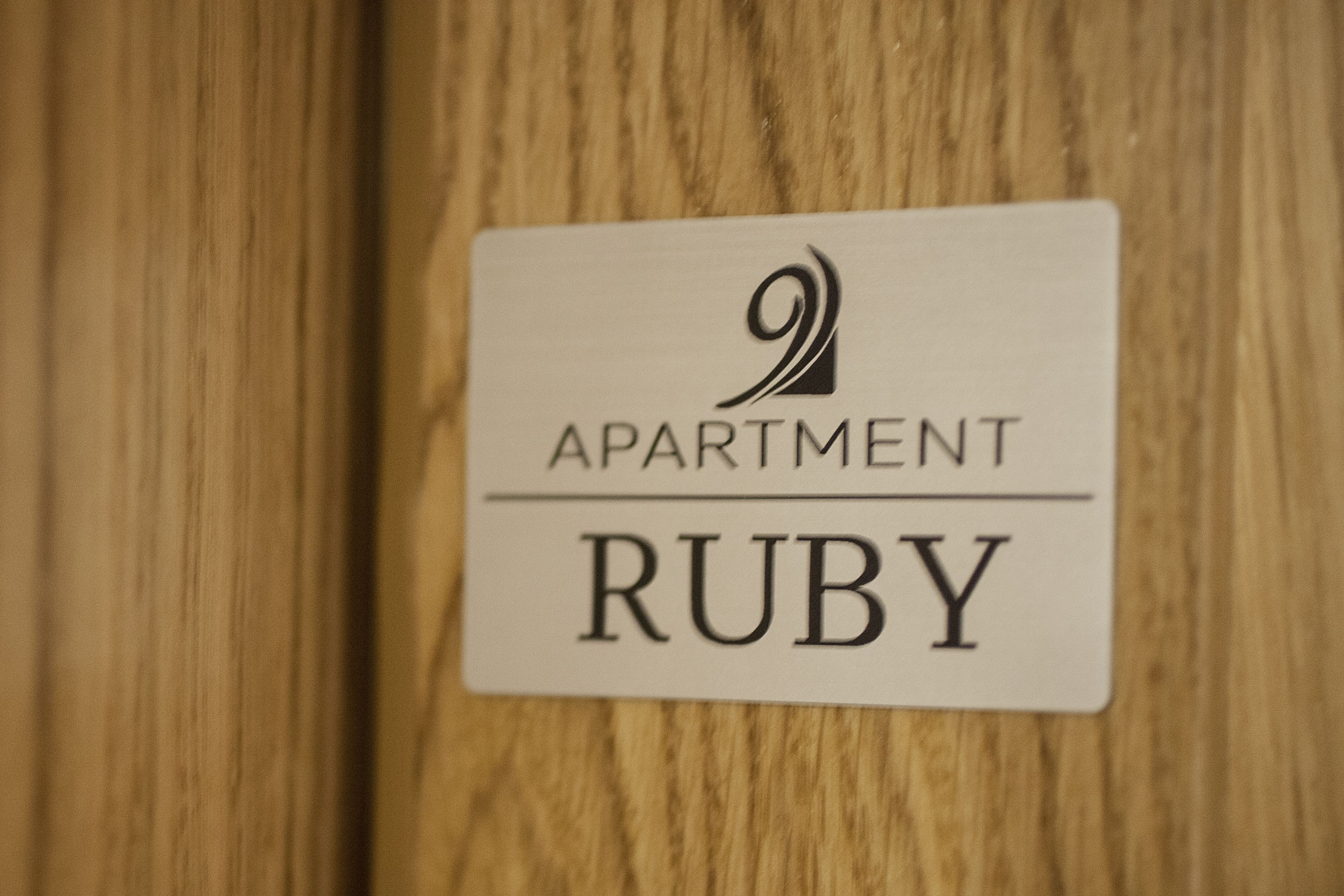 A sign with the text "Apartment Ruby" on a wooden surface.