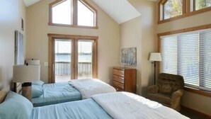 Un dormitorio con dos camas, un tocador, una silla y una ventana con persianas.