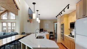 Una cocina moderna con una isla grande, armarios de madera y una zona de comedor con sofá y sillas.