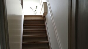 Un escalier en bois, avec des murs blancs et une porte en bas.