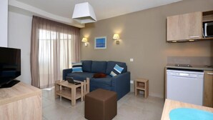 Una sala de estar moderna con un sofá, una mesa de centro, una televisión y una cocina con microondas y lavavajillas.