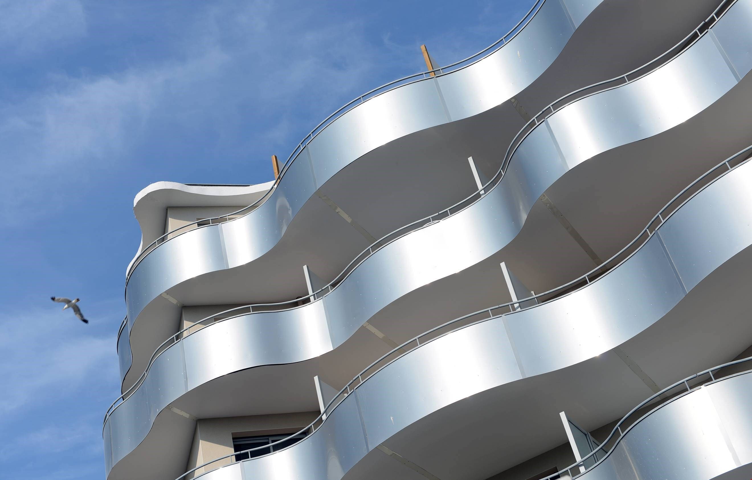 Un bâtiment moderne doté de balcons incurvés et surplombant un ciel dégagé.