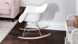 Ein modernes Zimmer mit einem weißen Schaukelstuhl, einem pinkfarbenen Sofa und einem an der Wand befestigten 'LOFT'-Schild.