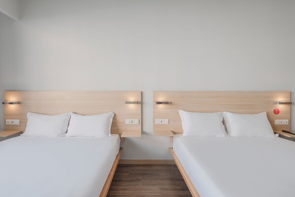 A hotel room with two single beds, wooden headboards, bedside tables, and wall-mounted light fixtures. - Moov Hotel Porto Centro (Porto)