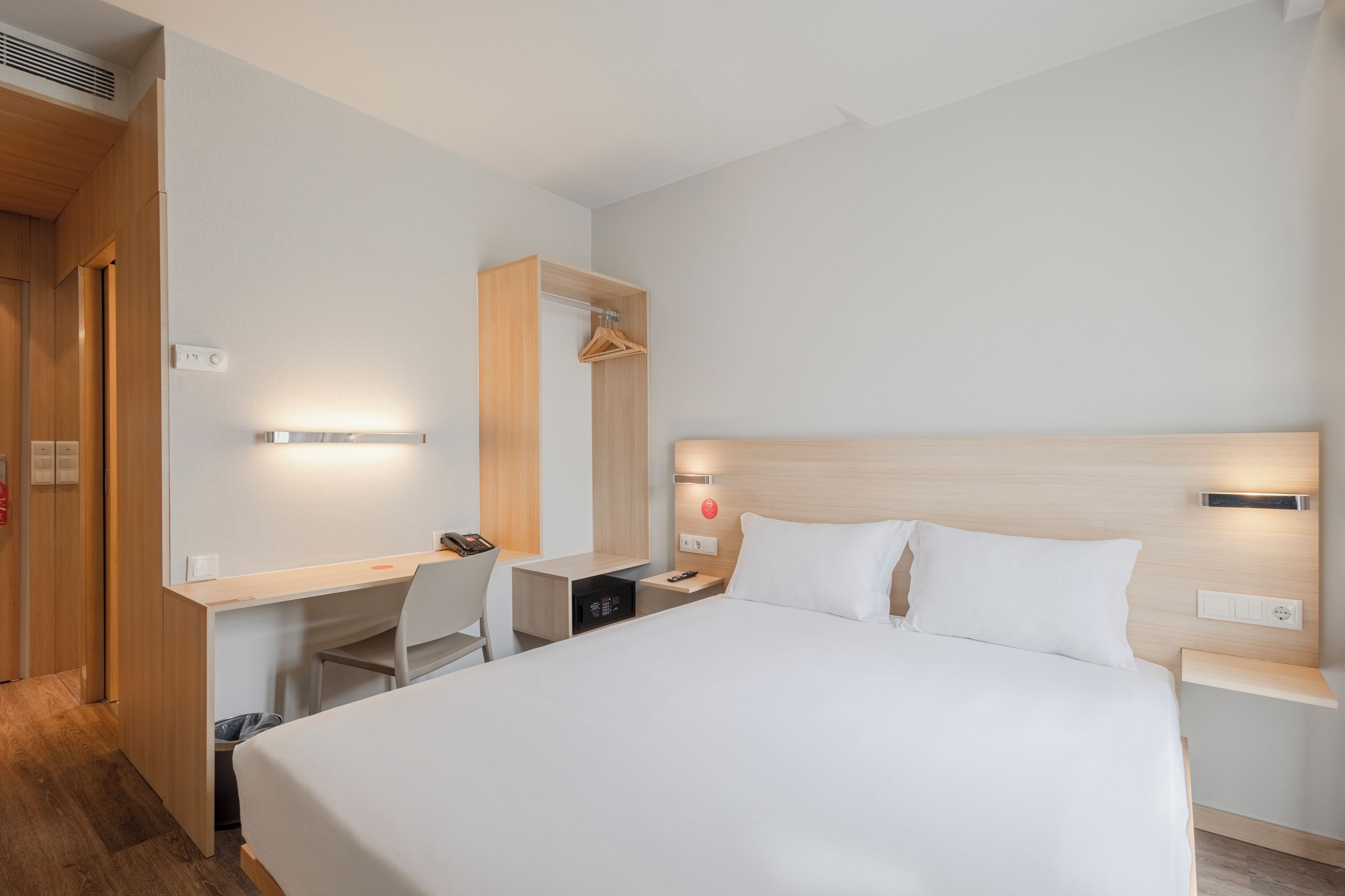 Een moderne hotelkamer met een groot bed, een bureau en een stoel.