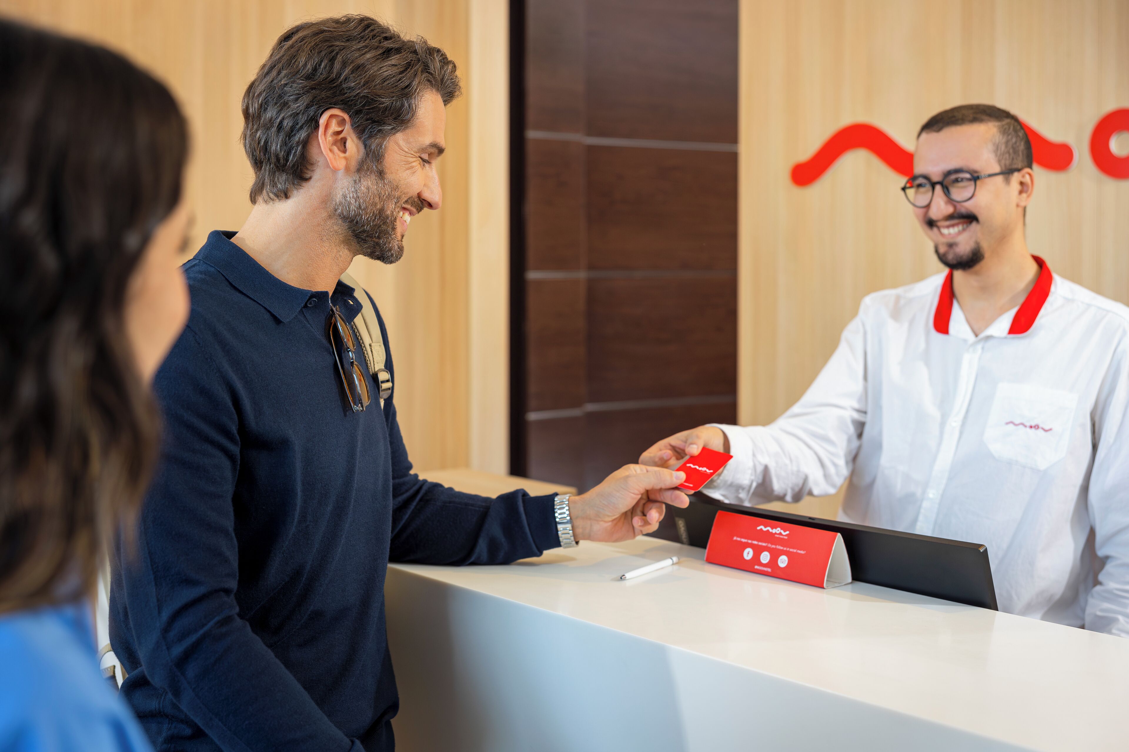 Una mesa de recepción con una placa, una tarjeta roja y un bolígrafo.