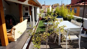 A rooftop terrace with a dining table, chairs, a sofa, and potted plants. - Loft with terrace historic center (Perpignan)