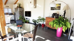 A modern kitchen with a built-in refrigerator, a dining area with a glass table and chairs, and a wooden cabinet with decorative items. - Loft with terrace historic center (Perpignan)