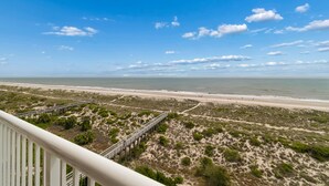 Blick auf einen Strand mit einer Holzsteg, Sanddünen und einem klaren Himmel.