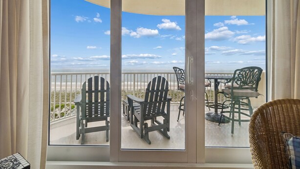 Ein Balkon mit Stühlen und einem Tisch, mit Blick auf einen Strand.