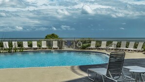 Ein Swimmingpool mit Liegestühlen und Blick aufs Meer.