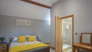 A bedroom with a bed, bedside table, nightstand, and a mirror. - Little Oak (Hereford)