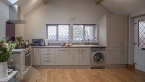 A modern kitchen with a central island, built-in appliances, and a large window. - Little Oak (Hereford)