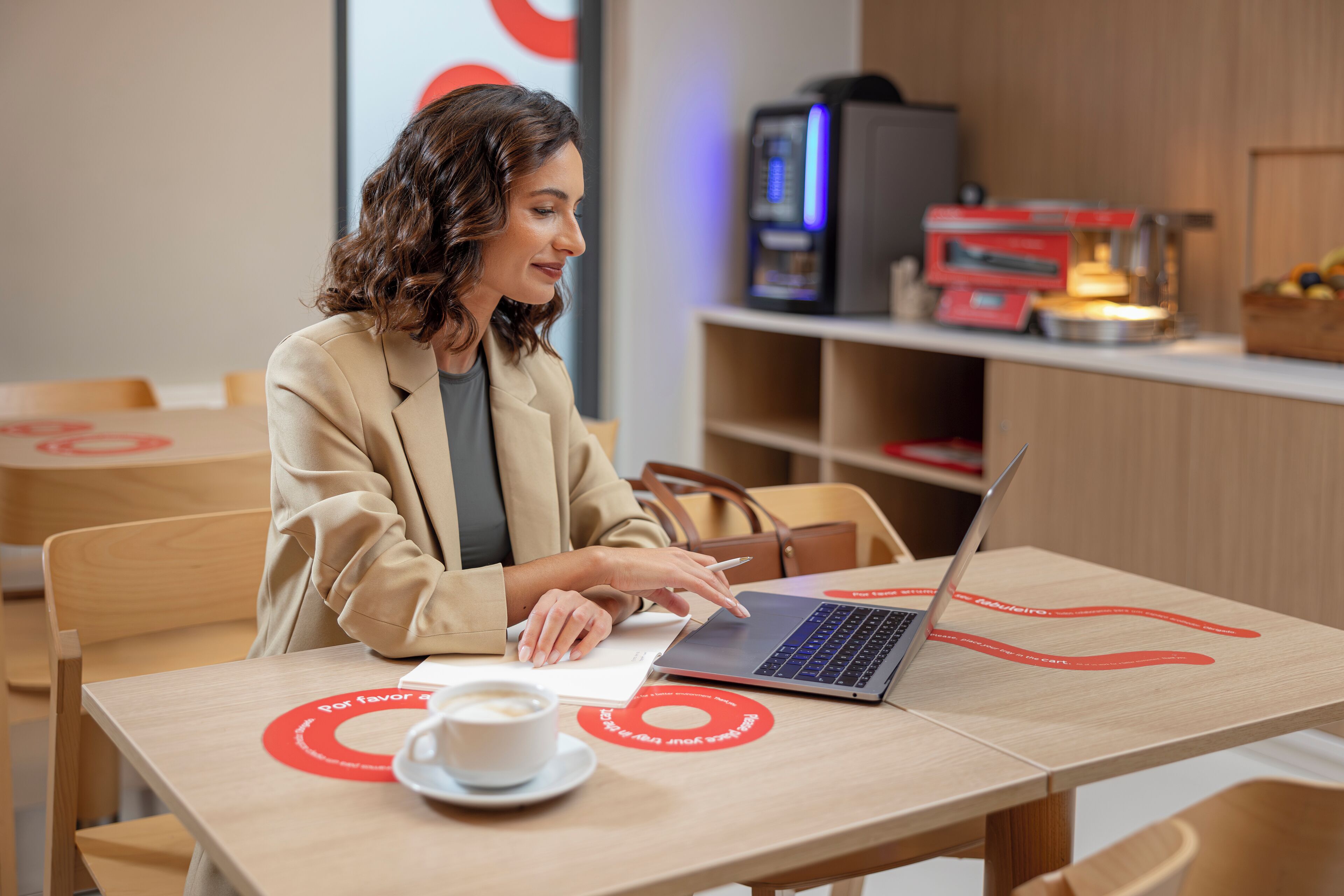 Una persona sentada a una mesa con un ordenador portátil, una taza de café y un menú.