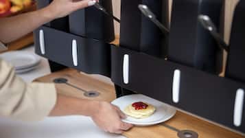 A person preparing a pastry on a plate, with a coffee machine in the background.