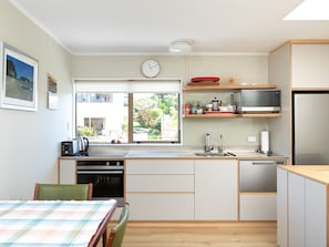 Una cocina compacta con zona de comedor, microondas, refrigerador y un reloj en la pared.