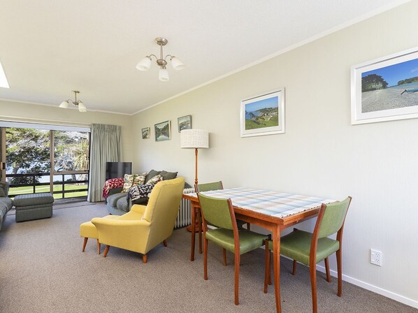 A spacious living room with a dining area, large windows, and a view of the outdoors.