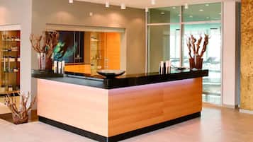 Un mostrador de recepción moderno con detalles de madera, una partición de vidrio y vistas al exterior a través de amplias ventanas.