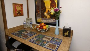 Une table avec une affiche représentant le parc de Yellowstone, un vase rempli de fleurs et un panier de fruits.