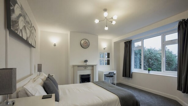 A modern hotel room with a bed, bedside table, desk, and a fireplace. - Raven House (Hereford)