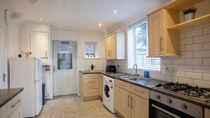 A modern kitchen with a built-in washing machine, a gas stove, and a sink. - Raven House (Hereford)