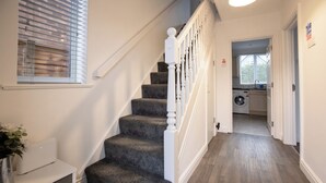 A staircase with a white railing leading to a laundry area. - Raven House (Hereford)