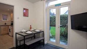 A modern kitchen with a dining area, a washing machine, and a TV mounted on the wall. - Raven House (Hereford)