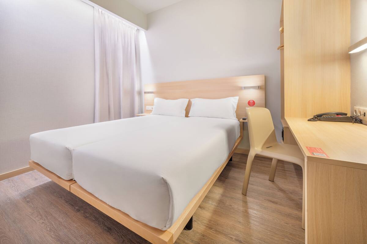 A hotel room with a bed, a desk, and a chair.