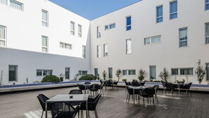 A courtyard with outdoor seating and a modern building facade. - Moov Hotel Évora (Évora)
