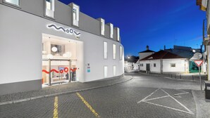 A modern building with a glass facade, a visible ATM, and a clear sky at dusk. - Moov Hotel Évora (Évora)