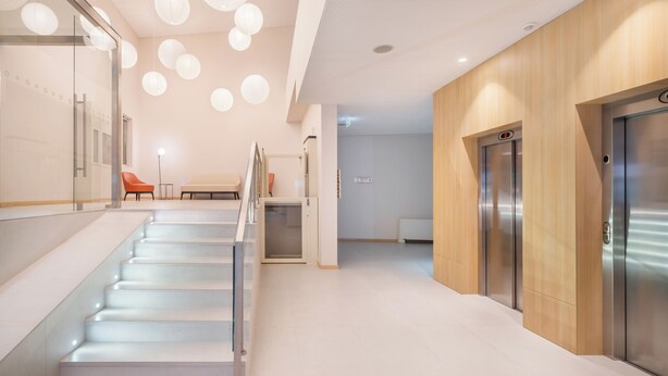 A modern interior with a staircase, elevators, and a seating area. - Moov Hotel Évora (Évora)