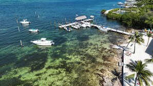 A marina with boats docked, clear shallow waters, and a beach with palm trees. - Spring Break in the Sun! Islamorada townhome w/ beach, pool in gated community! (Islamorada)