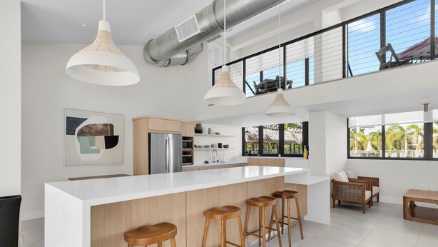 A modern kitchen with a central island, bar stools, and large windows offering views of the outdoors. - Spring Break in the Sun! Islamorada townhome w/ beach, pool in gated community! (Islamorada)