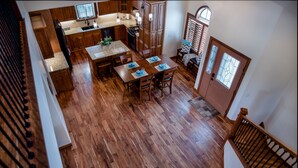 Una cocina amplia con armarios de madera, una mesa de comedor lista para cuatro personas y una escalera que lleva a un nivel superior.